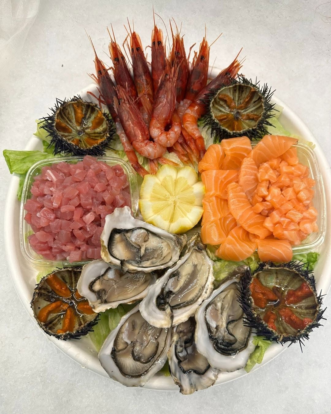 Piatto con tartare, gamberi, ostriche e ricci